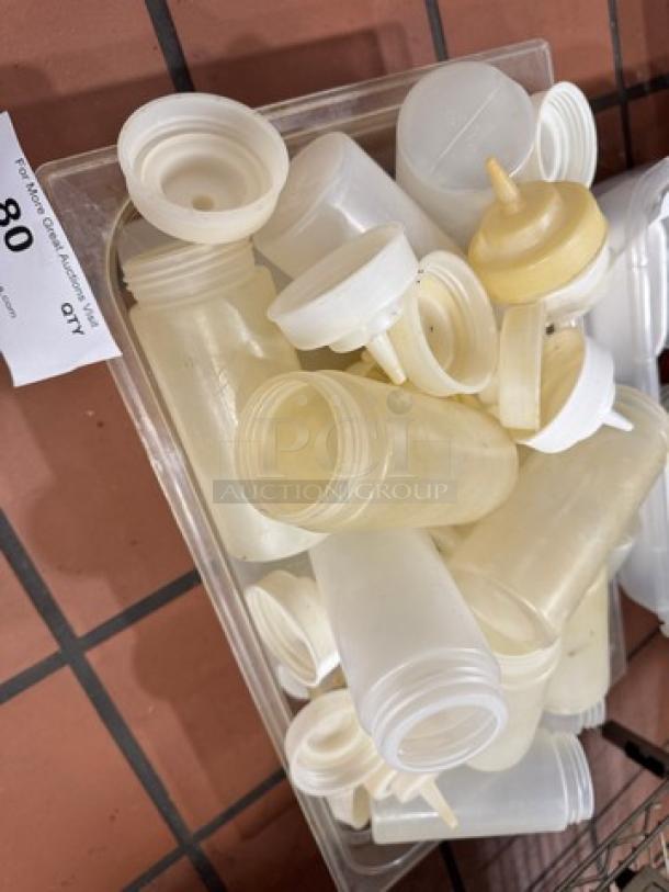 Various squeeze bottles with caps in a clear container, included as a single auction lot. Signs of use visible.