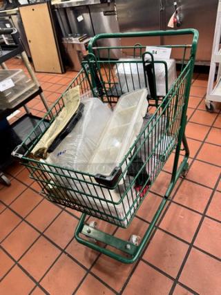 Green metal shopping cart with assorted contents, including plastic containers and bags. Good condition, suitable for various uses.