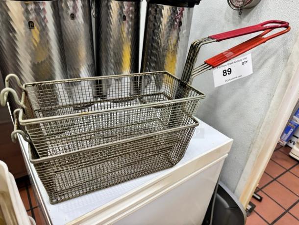 Metal fryer basket BIDX2 with red handle, mesh design, in good condition, auction tag with number 89 attached.