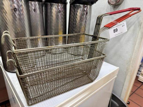 Metal fryer basket BIDX2 with red plastic handle, in used condition. Auction lot tag marked "89."