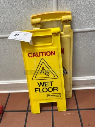 Lot of 2 yellow "WET FLOOR" signs by Rubbermaid, with caution symbols, in good condition. Auction tag indicates lot number 92.