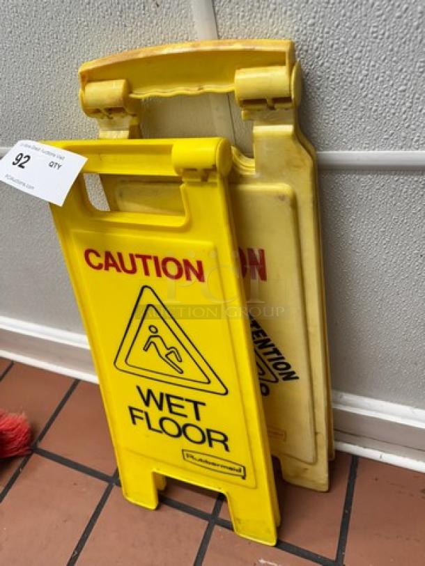 Lot of 2 yellow "WET FLOOR" signs with caution text, used condition, foldable design, including auction tag number 92.