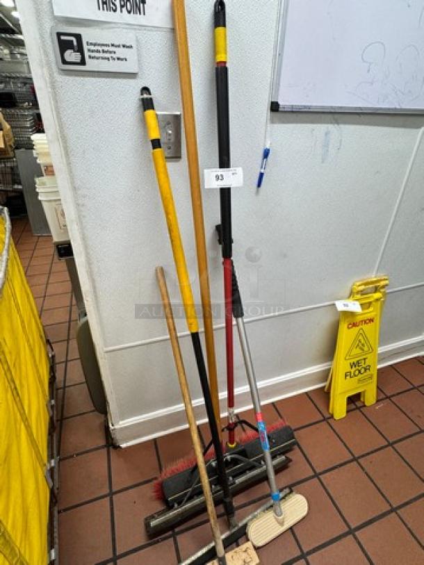 Assorted cleaning tools in used condition, including brooms and mops, grouped together.