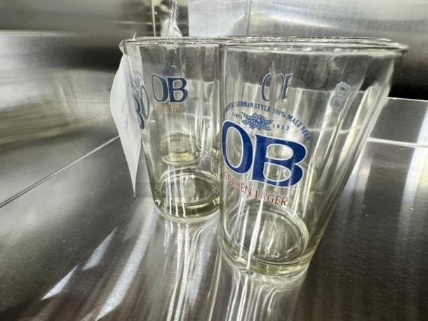Lot of 5 OB Golden Lager glasses, authentic German style, clear glass with blue and red branding, good condition.