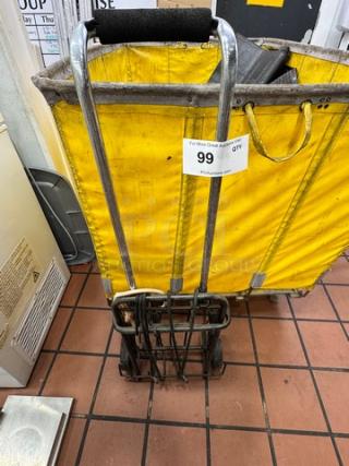 Rolling utility shopping cart with metal frame and yellow fabric bag. Features a cushioned handle. Auction tag reads "Lot 99."