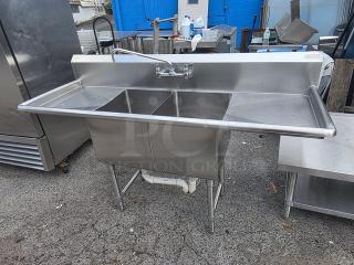 Stainless steel two compartment sink in good condition, integrated backsplash, and commercial faucet.