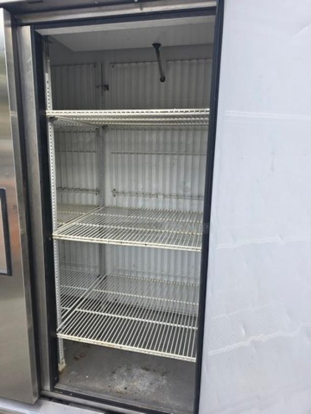 True T-72F T-Series reach-in freezer, 3-section, on casters, empty interior shelves, visible wear, stainless steel exterior.