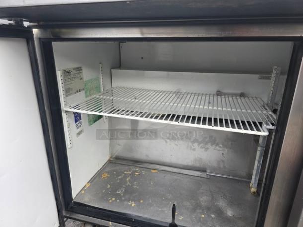 True QA-60-24M-B 60" refrigerated prep table, on casters. Features adjustable shelf, visible interior wear. Model label inside.