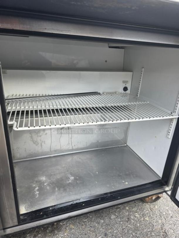 True QA-60-24M-B refrigerated prep table, 60 inches, on casters. Interior view shows shelves, clean condition.