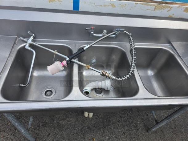 Stainless steel 3 compartment sink with faucet and sprayer. Includes drain fittings. Good condition, minor surface wear.