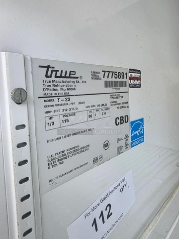 True T-23 reach-in solid swing door refrigerator, serial number 7775891, on casters, features product label with specifications.