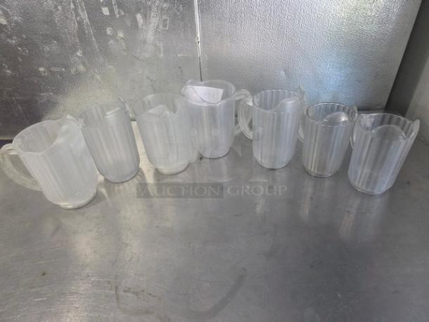 Lot of 7 clear plastic pitchers with handles, ribbed design. Good condition, suited for restaurant or catering use.