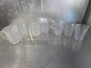 Lot of 7 clear plastic pitchers with handles, ribbed design. Good condition, suited for restaurant or catering use.