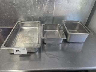 Lot of 3 stainless steel food pans in varying sizes, used condition, with auction tag "128" visible.