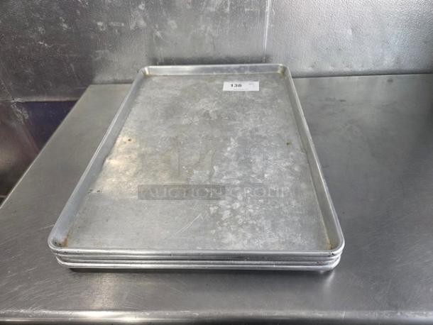 Lot of 4 aluminum baking sheet pans, used condition, visible surface wear. Stackable design, item tagged as "136."