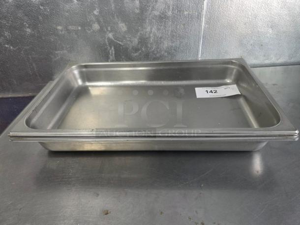 Lot of 4 stainless steel food pans, used condition. Includes visible label marked "142" on one pan. Durable and stackable.