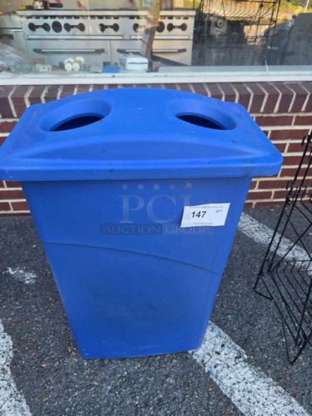 Blue recycling bin with dual circular openings and a rectangular body. Tag with number 147 is attached. Good condition.