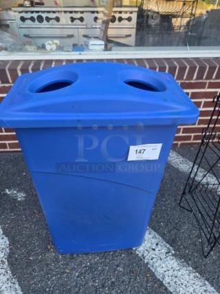 Blue recycling bin with dual circular openings and a rectangular body. Tag with number 147 is attached. Good condition.