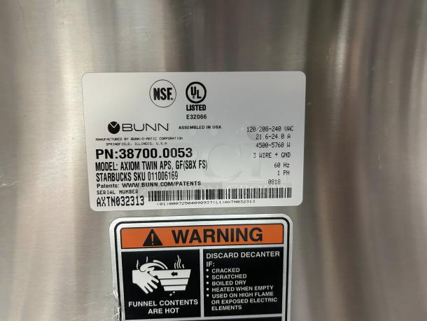 Bunn 38700.0013 Axiom APS Twin Airpot Coffee Brewer label, NSL and UL listed, voltage info, warning label visible.