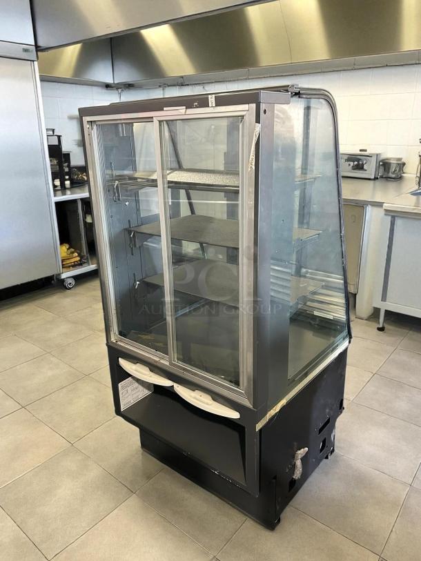 Structural Concepts 27" dry pastry display case in excellent condition, tested and working. Features glass panels, shelving, and metal frame.