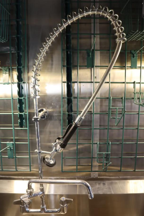 Alt text: Stainless steel faucet inside a Cruising Kitchens 24' Enterprise food trailer. Green racks in the background.