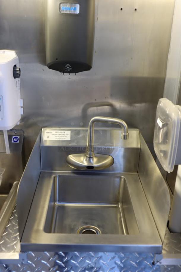 Stainless steel sink in new Cruising Kitchens food trailer, featuring a modern faucet and wall-mounted soap dispenser.