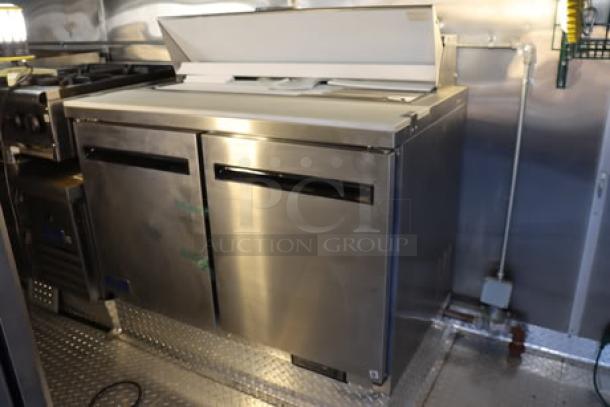 NEW Cruising Kitchens 24' food trailer interior with stainless steel equipment, including counters and appliances.