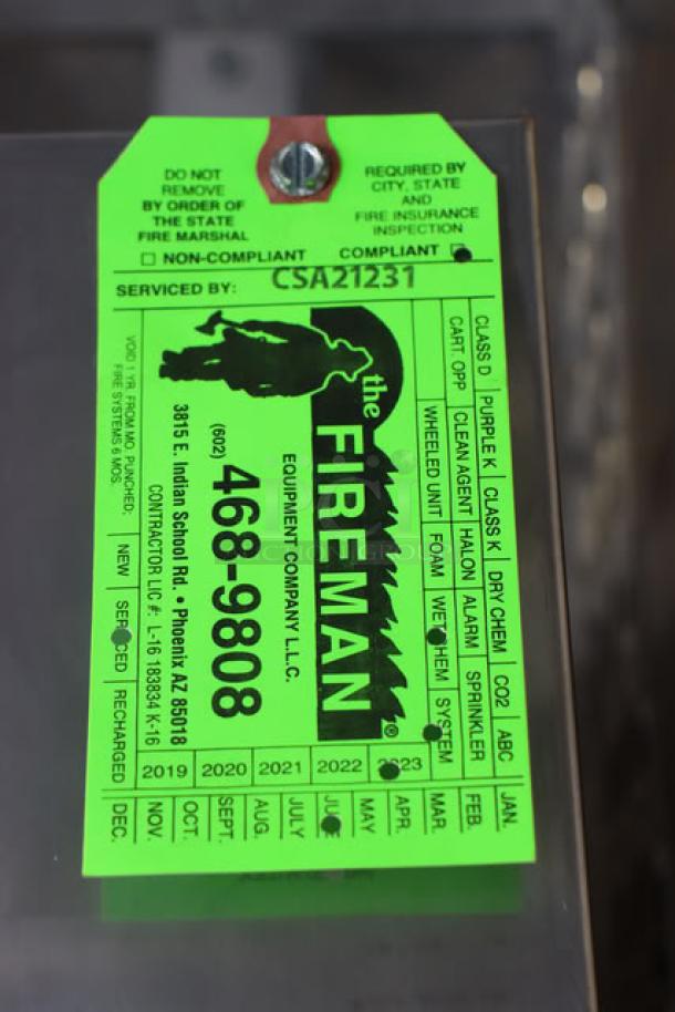Green inspection tag labeled "The Fireman Equipment Company LLC" with contact info and compliance checklist.