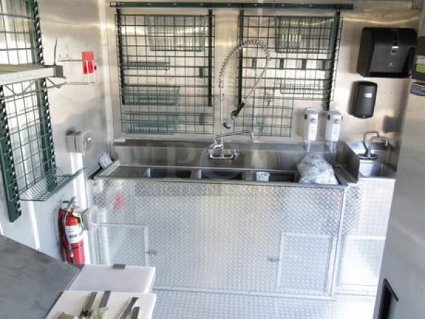 Brand new 2023 24-ft Cruising Kitchens food trailer kitchen interior, stainless steel sink, diamond plate finish, safety equipment.