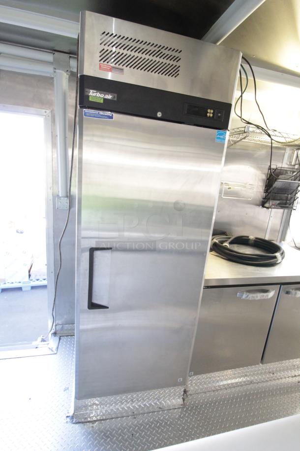 Brand new 2023 Cruising Kitchens 24 ft. food trailer interior, featuring a commercial Turbo Air refrigerator and stainless steel counters.