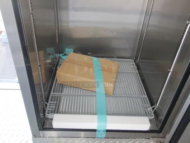 Interior view of a new 2023 Cruising Kitchens Enterprise Food Trailer with stainless steel shelving, packaged item strapped in place.