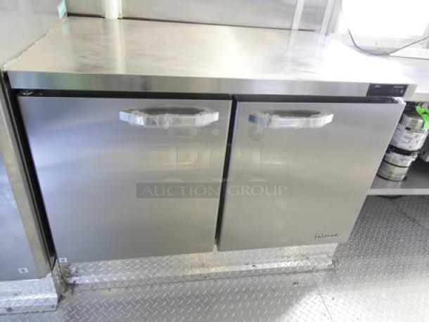 Stainless steel double-door cooler in a 2023 Cruising Kitchens food trailer. Commercial-grade with sleek handles.
