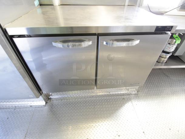 Stainless steel commercial refrigerator in a new 2023 Cruising Kitchens 24 ft. mobile kitchen trailer.