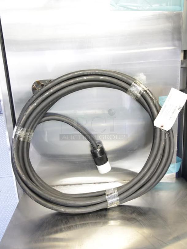 Coiled heavy-duty black cable with connector, part of a 2023 Cruising Kitchens 24 ft mobile kitchen. Includes attached tag.
