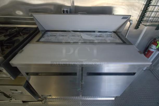 Brand new 2023 Cruising Kitchens 24 ft. Enterprise food trailer interior with stainless steel cooler and under-storage.