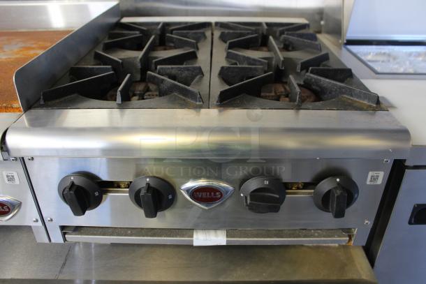 Stainless steel Wells commercial-grade range with four burners, featuring control knobs and durable construction.