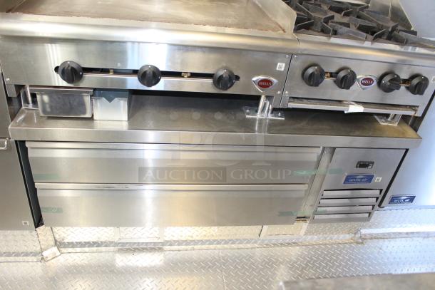 Stainless steel commercial range and griddle with Wells brand control knobs and Arctic Air cooler in a mobile kitchen setup.