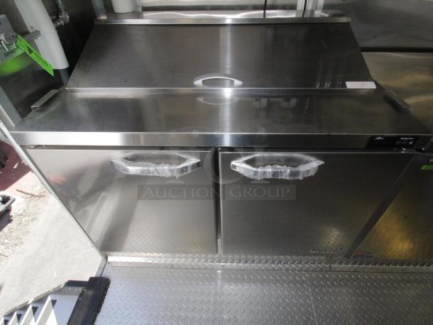 Stainless steel countertop and refrigerated cabinet in a 2023 Cruising Kitchens 24 Ft. Enterprise Food Trailer, new condition.