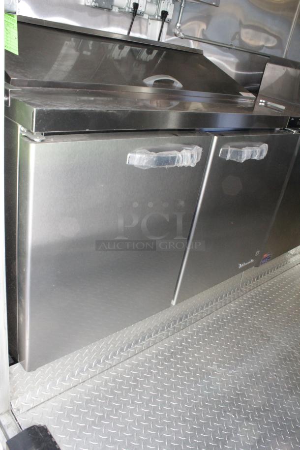 Cruising Kitchens 2023 24-ft food trailer interior, featuring new stainless steel commercial refrigerators with protective wrap.