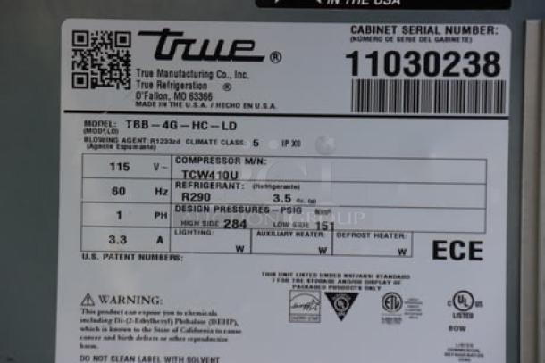 True TBB-4G-HC-LD back bar refrigerator, black finish, model and serial number tags visible. Outer glass pane broken.