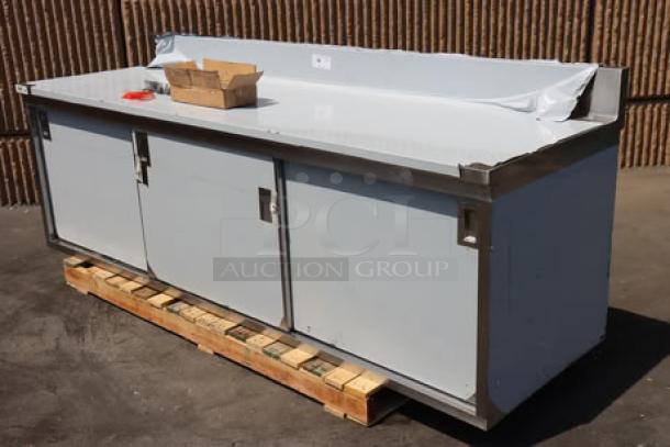 Brand new Regency 600EBTB3096D stainless steel table with enclosed base, sliding doors, adjustable midshelf, and 6" backsplash.