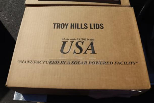 Cardboard box with text "Troy Hills Lids," indicating manufacture in the USA in a solar-powered facility.