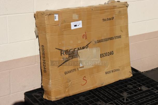 Brand new Regency 600ES3024G 30" x 24" stainless steel equipment stand, 16-gauge, in original packaging with visible scratches and dents.