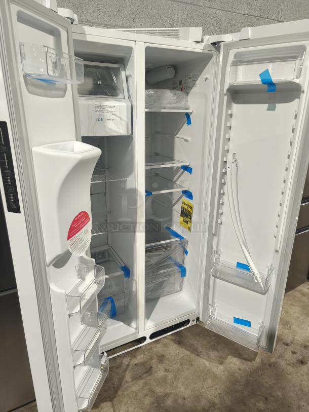 BRAND NEW Frigidaire 22.3 Cu. Ft. Side-by-Side Refrigerator, Model FRSS2323AW. Interior view, protective film visible.