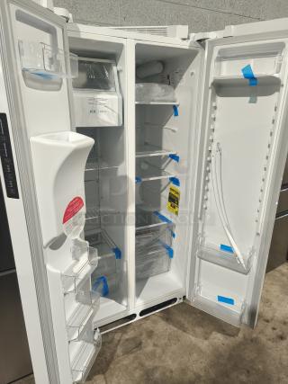 BRAND NEW Frigidaire 22.3 Cu. Ft. Side-by-Side Refrigerator, Model FRSS2323AW. Interior view, protective film visible.