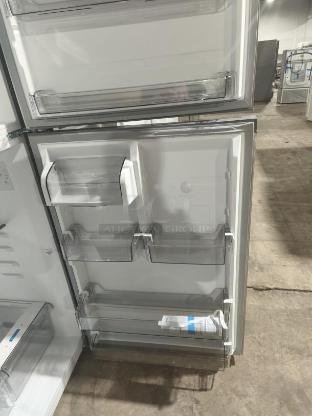 Midea MRT18D3BST 18.1 cu ft top-freezer refrigerator, new condition, open door view showing interior shelves and door bins.