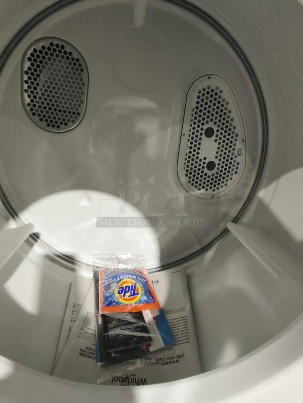 Whirlpool WET4024HW 1.6 cu. ft. stacked laundry center, new condition, interior view with manual and Tide sample.