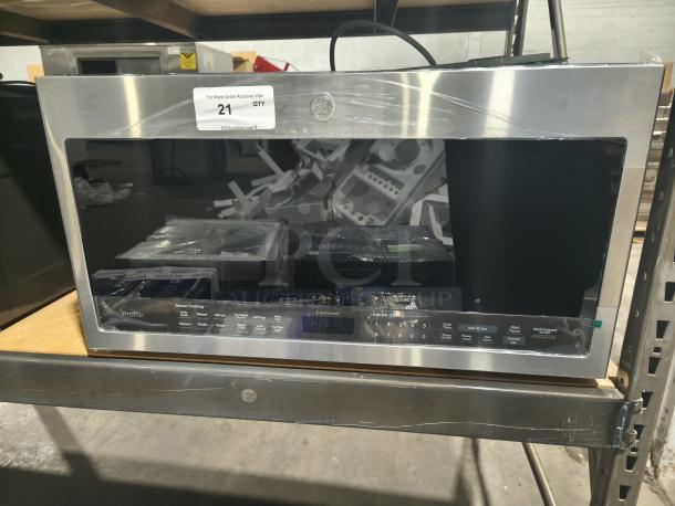 BRAND NEW SCRATCH AND DENT - GE Profile PVM9005SJ8SS 2.1 cu ft Over-the-Range Sensor Microwave Oven in stainless steel, visible protective film.