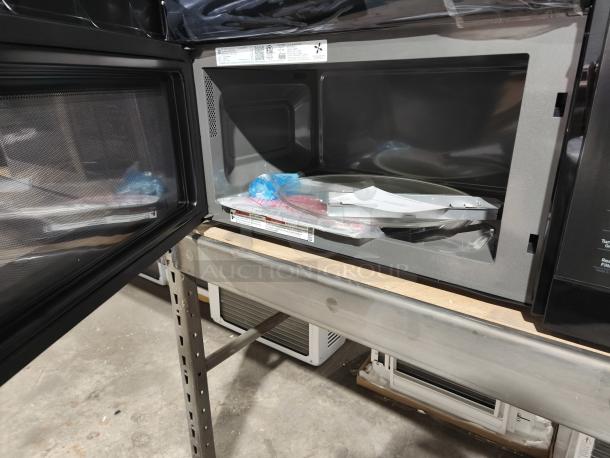 Brand new GE JVM7195DKBB 1.9 cu ft over-the-range sensor microwave oven, interior view, with packaging materials.