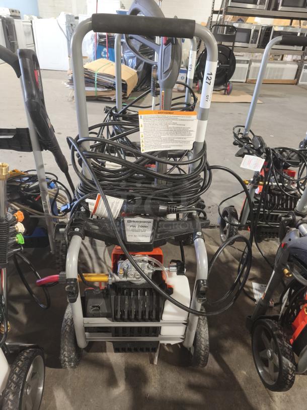 Husqvarna PW2300 Electric Pressure Washer, tested and working, features sturdy frame, hose storage, and user manual.